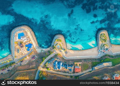 Aerial view of beautiful sandy beach, blue sea, restaurants on the promenade, pool, umbrellas, swimming people in clear water, green trees at sunset in summer. Top view of seafront. Tropical landscape