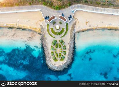 Aerial view of beautiful sandy beach, clear blue sea, promenade, swimming people in clear water, green trees at sunset in summer. Top view of seafront. Tropical landscape. View from drone of sea shore