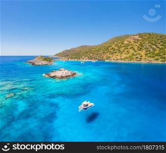 Aerial view of beautiful yacht on the sea at sunny day in summer. Akvaryum koyu in Turkey. Top view of luxury boat, lagoon with transparent blue water, rocks, sky, mountain and green trees. Travel