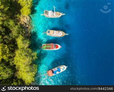 Aerial view of beautiful yachts and boats on the sea at summer sunny day. Fethiye lagoons, Turkey. Top view of bay, luxury yachts, sailboats, clear blue water, beach, mountain and green forest. Travel