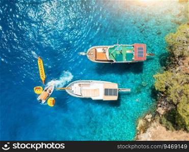 Aerial view of beautiful yachts and boats on the sea bay at summer sunny day. Fethiye lagoons, Turkey. Top view of luxury yachts, sailboats, clear blue water, sand, stones and green forest. Tropical