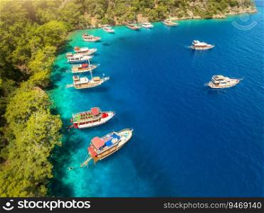 Aerial view of beautiful yachts and boats on the sea bay at sunset in summer. Fethiye lagoons, Turkey. Top view of luxury yachts, sailboats, clear blue water, sand, stones and green trees. Tropical
