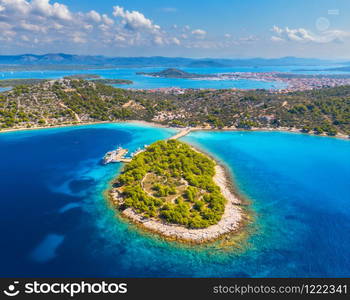 Aerial view of beutiful small island in sea bay at sunny day in summer in Murter, Croatia. Top view of transparent blue water, green trees, mountain, sandy beach, boats and yachts. Tropical landscape