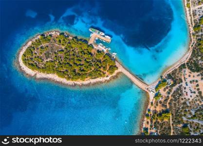 Aerial view of beutiful small island in sea bay at sunny day in summer in Murter, Croatia. Top view of transparent blue water, green trees, mountain, sandy beach, boats and yachts. Tropical landscape