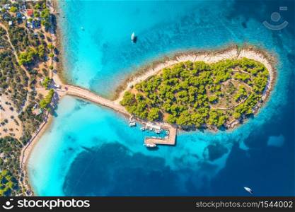 Aerial view of beutiful small island in sea bay at sunny day in summer in Murter, Croatia. Top view of clear blue water, green trees, mountain, sandy beach, boats and yachts. Tropical landscape