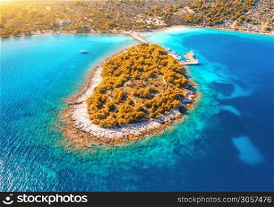 Aerial view of beutiful small island in sea bay at sunset in autumn in Murter, Croatia. Top view of clear blue water, orange trees, mountain, sandy beach, boats and yachts in fall. Tropical landscape