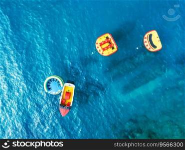 Aerial view of boat on blue sea at sunrise in summer. Travel in Krk island, Croatia. Top drone view of inflatable rings, sea lagoon, transparent azure water. Seascape. Top view. Water activities
