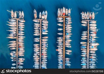 Aerial view of boats and luxure yachts in dock at sunset in summer in Pula, Croatia. Colorful landscape with sailboats and motorboats in sea bay, jatty, clear blue sea. Drone view of harbor. Travel