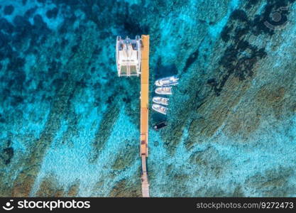 Aerial view of boats and luxure yachts in dock at sunset in summer in Sardinia, Italy. Colorful landscape with sailboats and motorboats in sea bay, jatty, clear blue sea. Top view of harbor. Travel