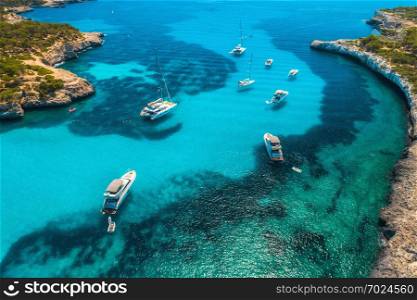 Aerial view of boats and luxury yachts in transparent sea at sunny day in Mallorca, Spain in summer. Sea coast. Colorful seascape with marina bay, azure water. Top view from drone of shore. Travel