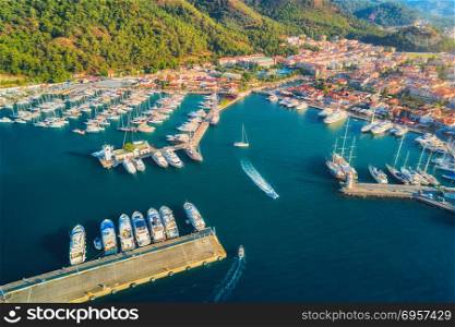 Aerial view of boats and yachts at sunset. Aerial view of boats and yachts at sunset in Turkey. Colorful landscape with boats in marina bay, sea, mountains, forest, blue sky. Top view from drone of harbor with luxury yacht, sailboat. Travel