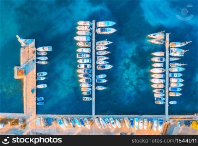 Aerial view of boats and yachts in port in beautiful old city at sunset in Croatia in summer. Landscape with motorboats in harbor, clear blue sea, cars, on the road. Top view