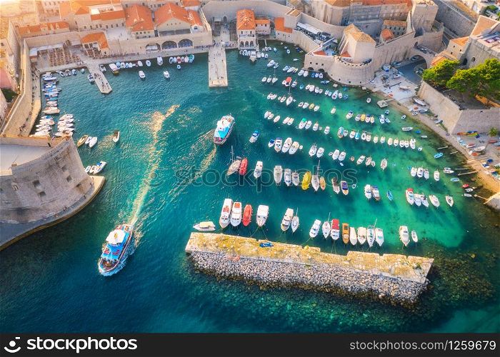 Aerial view of boats and yachts in port in old city in Dubrovnik at sunset. Summer landscape with buildings, motorboats in harbor, transparent blue sea. Beautiful architecture. View from above. Travel