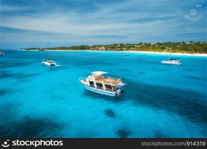 Aerial view of boats and yachts on tropical sea coast with white sandy beach at bright sunny summer day . Indian Ocean in Africa. Landscape with boat, palm trees, transparent blue water, sky. Top view