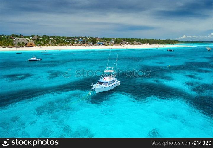 Aerial view of boats and yachts on tropical sea coast with white sandy beach at bright sunny summer day . Indian Ocean in Africa. Landscape with boat, palm trees, transparent blue water, sky. Top view