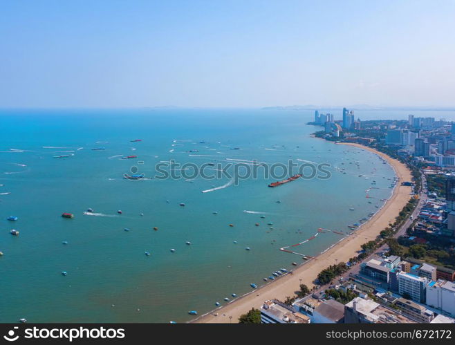 Aerial view of boats in Pattaya sea, beach, and urban city with blue sky for travel background. Chonburi, Thailand.