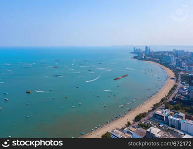 Aerial view of boats in Pattaya sea, beach, and urban city with blue sky for travel background. Chonburi, Thailand.