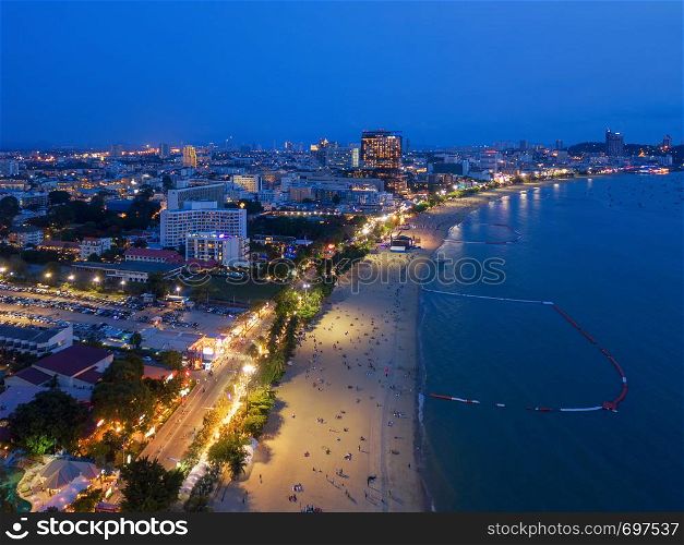 Aerial view of boats in Pattaya sea, beach at night, and urban city with blue sky for travel background. Chon buri Province, Thailand.
