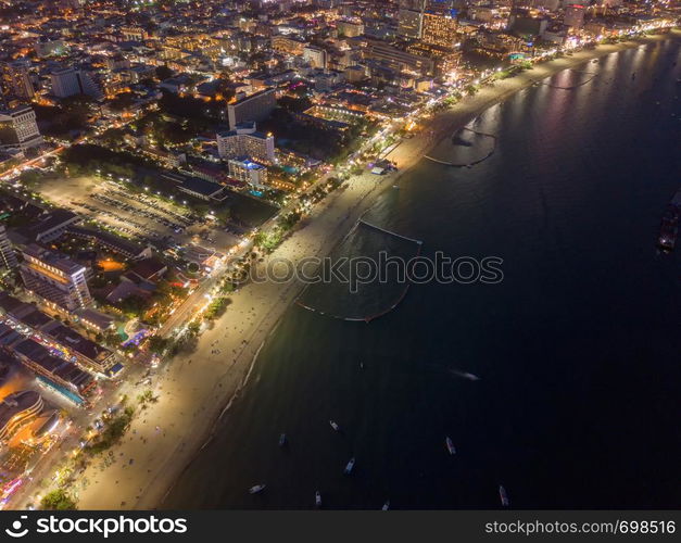 Aerial view of boats in Pattaya sea, beach at night, and urban city with blue sky for travel background. Chon buri Province, Thailand.