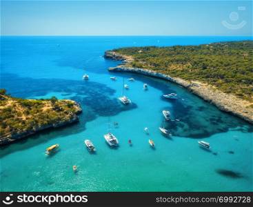 Aerial view of boats, luxury yachts, green trees and transparent sea in sunny bright day in Mallorca, Spain. Summer landscape with bay, azure water, beach, blue sky. Balearic islands. Top view. Travel