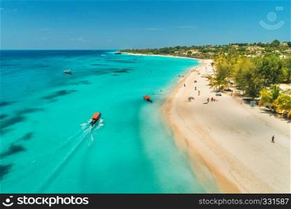 Aerial view of boats on tropical sea coast with sandy beach at sunny day. Summer holiday on Indian Ocean, Zanzibar, Africa. Landscape with boat, palm trees, transparent blue water, hotels. Top view