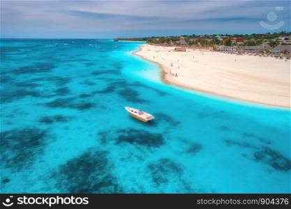 Aerial view of boats on tropical sea coast with sandy beach at sunny day. Summer holiday. Indian Ocean in Zanzibar, Africa. Landscape with boat, palm trees, transparent blue water, sky. Top view