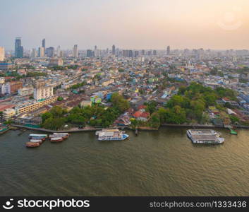 Aerial view of boats with Chao Phraya River, Bangkok Downtown skyline. Thailand. Financial district and business centers in smart urban city. Skyscraper and high-rise buildings at sunset.