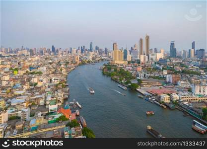 Aerial view of boats with Chao Phraya River, Bangkok Downtown skyline. Thailand. Financial district and business centers in smart urban city. Skyscraper and high-rise buildings at sunset.
