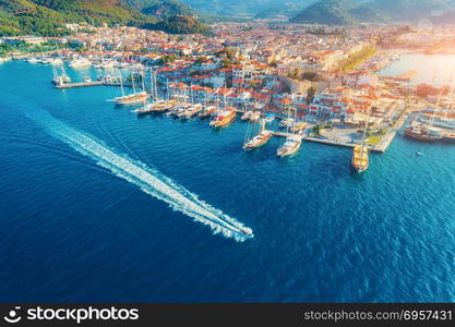 Aerial view of boats, yahts, floating ship and architecture. Aerial view of boats, yahts, floating ship and beautiful architecture at sunset in Marmaris, Turkey. Landscape with boats in marina bay, blue sea, city. Top view of harbor with yacht and sailboat.