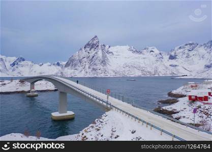Aerial view of bridge and road in Lofoten islands, Nordland county, Norway, Europe. White snowy mountain hills and trees, nature landscape background in winter season. Famous tourist attraction