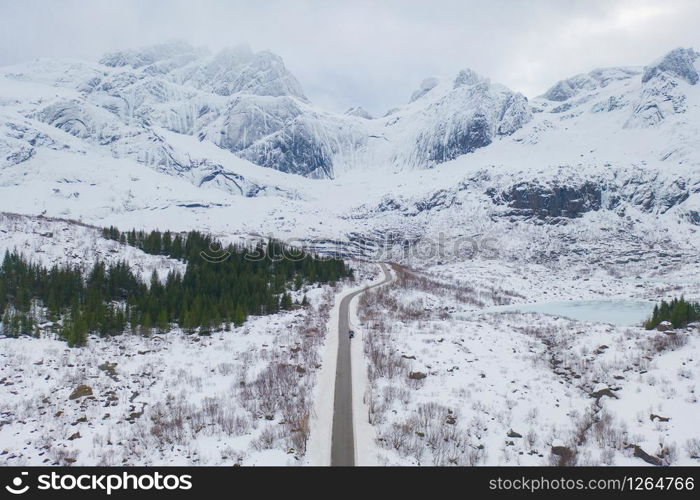 Aerial view of bridge and road in Lofoten islands, Nordland county, Norway, Europe. White snowy mountain hills and trees, nature landscape background in winter season. Famous tourist attraction