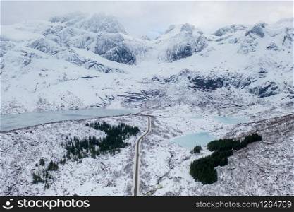 Aerial view of bridge and road in Lofoten islands, Nordland county, Norway, Europe. White snowy mountain hills and trees, nature landscape background in winter season. Famous tourist attraction