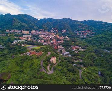 Aerial view of buildings in Jiufen village on mountain hill with green natural forest trees in rural area of New Taipei City, Taiwan