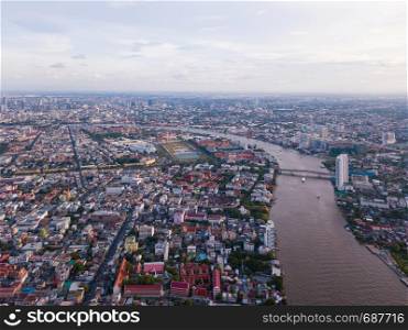 Aerial view of buildings with Chao Phraya River in transportation concept. Bangkok skyline background, Urban city in downtown area at sunset, Thailand.