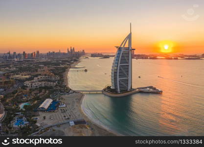 Aerial view of Burj Al Arab Jumeirah Island or boat building, Dubai Downtown skyline, United Arab Emirates or UAE. Financial district in urban city. Skyscrapers at sunset.