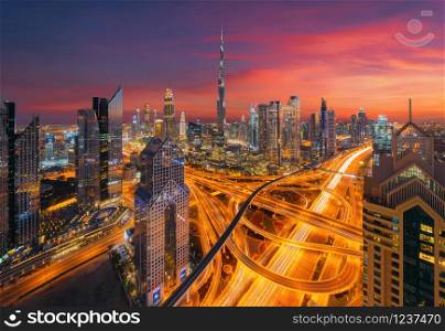 Aerial view of Burj Khalifa in Dubai Downtown skyline and highway, United Arab Emirates or UAE. Financial district and business area in smart urban city. Skyscraper and high-rise buildings at night.