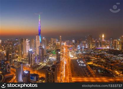 Aerial view of Burj Khalifa in Dubai Downtown skyline and highway, United Arab Emirates or UAE. Financial district and business area in smart urban city. Skyscraper and high-rise buildings at night.