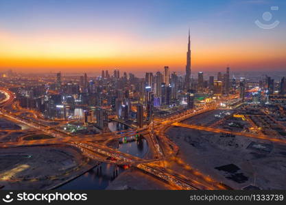 Aerial view of Burj Khalifa in Dubai Downtown skyline and highway, United Arab Emirates or UAE. Financial district and business area in smart urban city. Skyscraper and high-rise buildings at night.