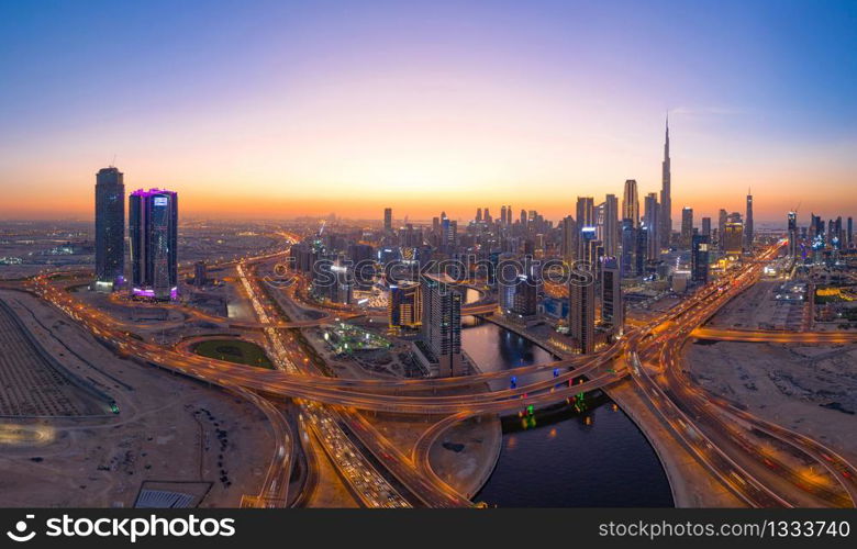 Aerial view of Burj Khalifa in Dubai Downtown skyline and highway, United Arab Emirates or UAE. Financial district and business area in smart urban city. Skyscraper and high-rise buildings at night.