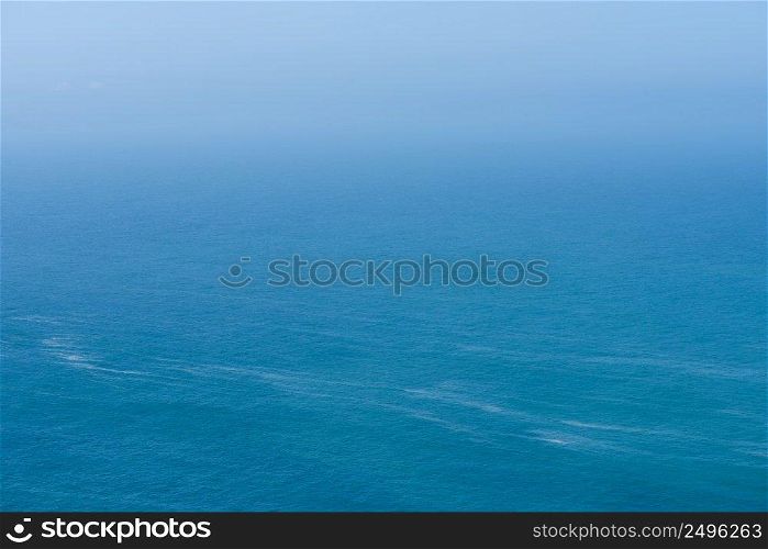 Aerial view of calm infinite ocean and blue sky background 
