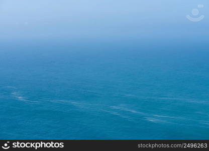 Aerial view of calm infinite ocean and blue sky background 