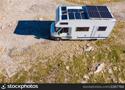 Aerial view of camper with many solar photovoltaic panels on roof camping on nature. Renewable free energy. Elecrticity on caravan holidays.. Caravan solar panels on roof camping on nature. Aerial view