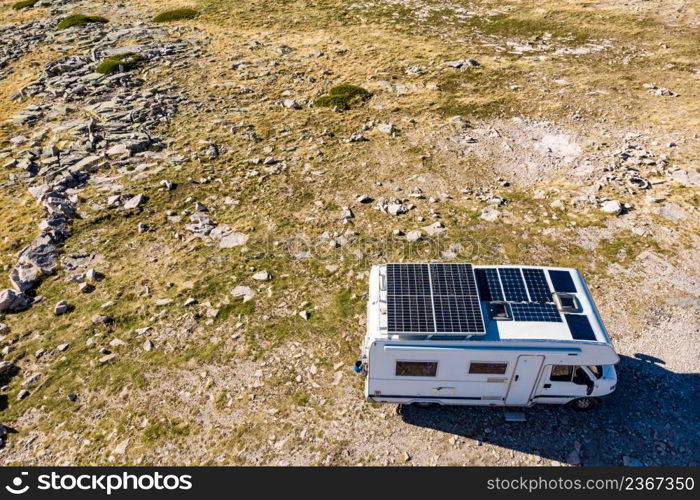 Aerial view of camper with many solar photovoltaic panels on roof camping on nature. Renewable free energy. Elecrticity on caravan holidays.. Caravan solar panels on roof camping on nature. Aerial view