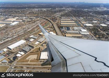 Aerial view of cargo trains and contrainers at the terminal railway which look through airplane windows,Aircraft Wing over cityscape,street and express way at the afternoon time,transportation concept
