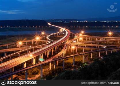 Aerial view of cars driving on complex highway or freeway. Bridge roads or streets in structure of architecture and transportation concept. Top view. Urban city, Taichung at night, Taiwan.