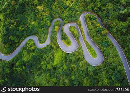 Aerial view of cars driving on curved, zigzag road or street on mountain hill with green natural forest trees in rural area of New Taipei City, Taiwan