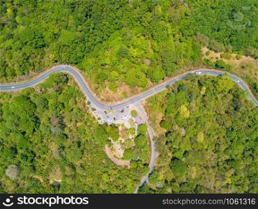 Aerial view of cars driving on curved, zigzag road or street way path on mountain hill with green natural green forest trees in Phuket City, Thailand.