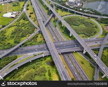 Aerial view of cars driving on highway junctions. Bridge roads with green garden and trees in connection of architecture concept. Top view. Urban city, Taipei, Taiwan.