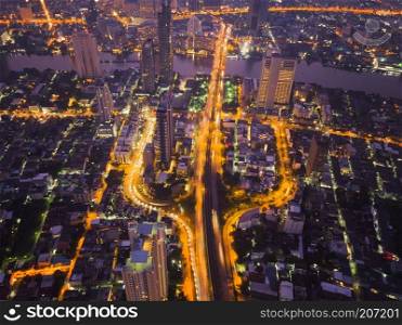 Aerial view of cars on Taksin Bridge in financial district and skyscraper buildings in transportation concept. Top view of urban city at night, Sathorn road, Bangkok. Downtown area, Thailand.