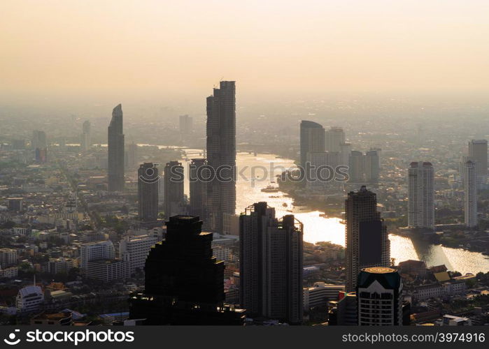 Aerial view of Chao Phraya River, Bangkok Downtown. Financial district and business centers in smart urban city in Asia. Skyscraper and high-rise buildings at sunset.